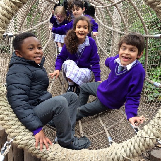 children sitting in a rope tunnel