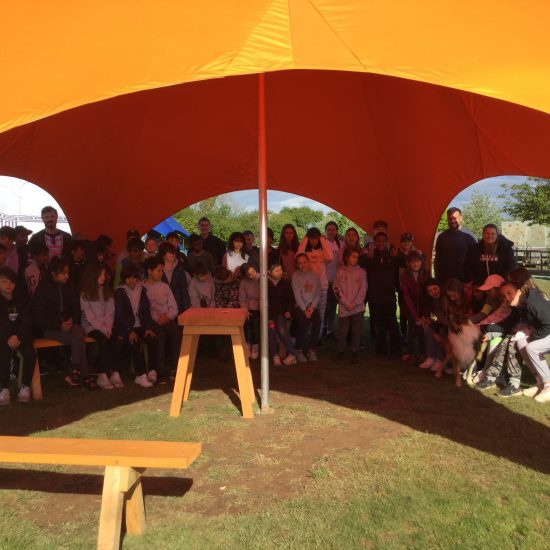 children and teachers standing under a tent