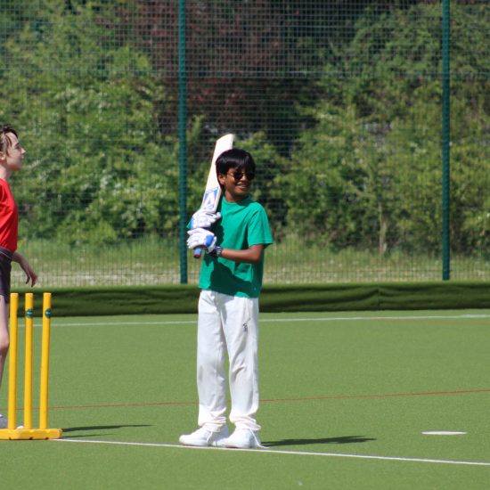 a child with sunglasses holding a cricket bat