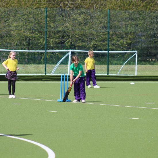 children on an astro turf playing cricket