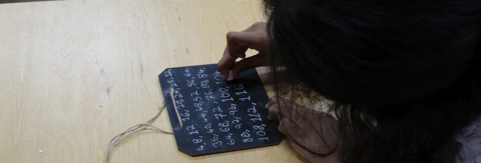 a girl from a private school in Surrey writing on a chalk board
