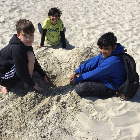 3 students playing with sand