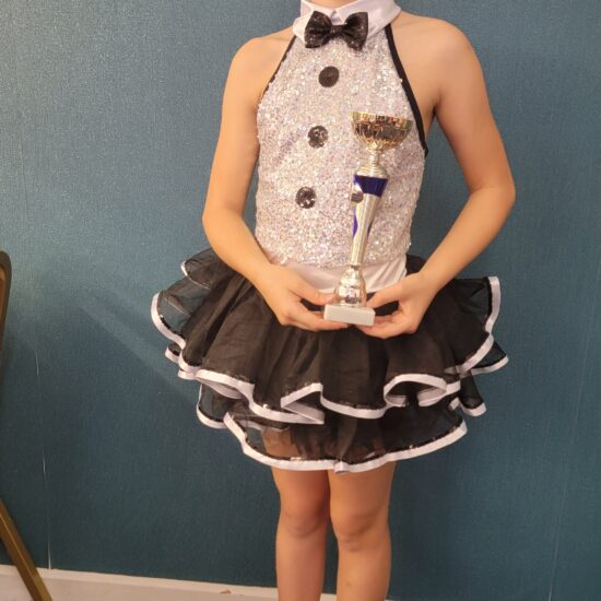 student holding a trophy in ballet outfit